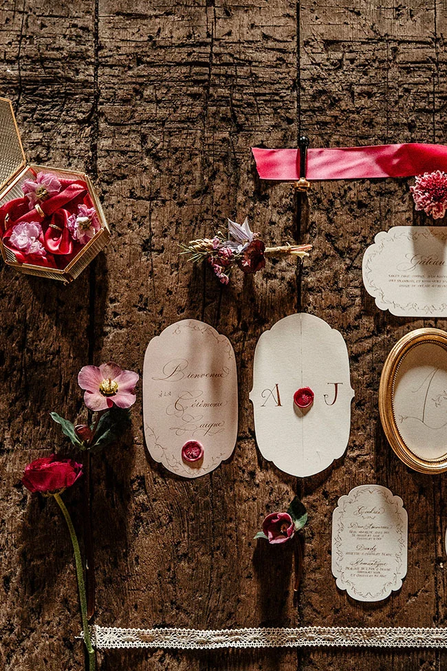 Magnifique scène de mariage vintage avec une touche magenta, des invitations soignées et des détails romantiques.