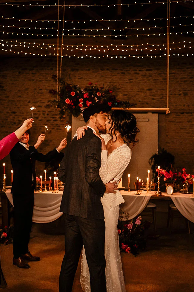 Un couple de mariée et de marié partageant un baiser intime au milieu d'une ambiance romantique avec des chandelles et