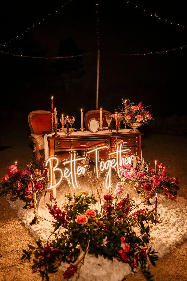 Un scène romantique avec un arbre de mariage vintage et magenta, illuminé par des cierges et des fleurs rouges, avec un
