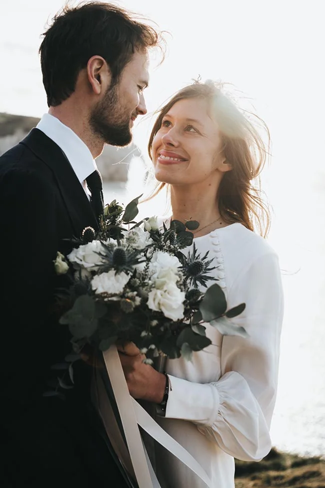 Un couple heureux se regarde l'un l'autre avec tendresse, le mari tenant un bouquet de fleurs sombres, le scène