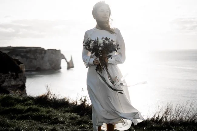 Élégante mariée blanche, bouquet sombre, scène romantique du falaise d'Étretat.