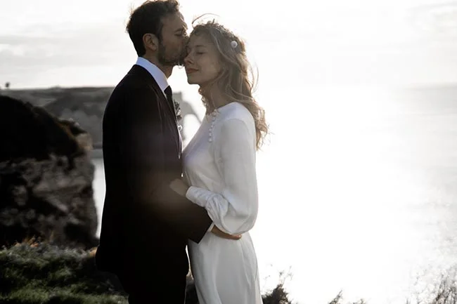 Un couple romantique partage un moment intime sur une falaise à Etretat, au bord de l'océan.