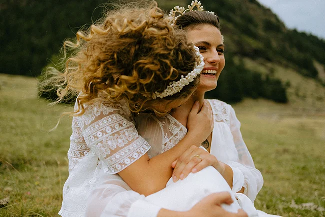 Une jeune mariée brune dans un robe blanche délicieuse s'embrasse tendrement avec son mari dans un décor pittoresque des Pyrénées.