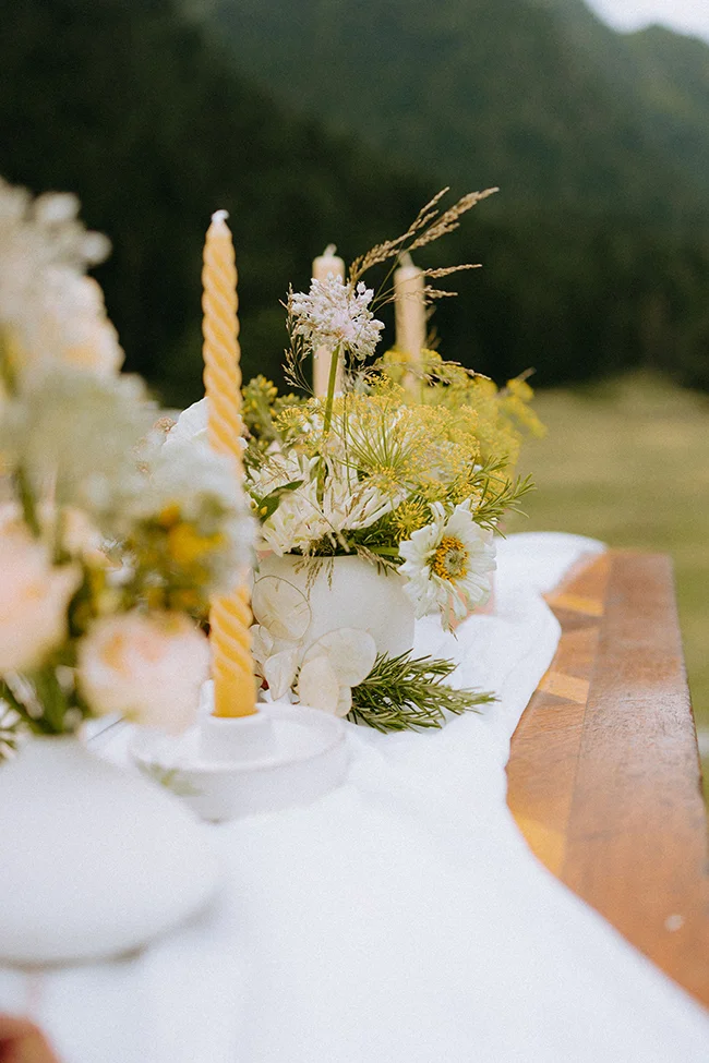 Un décor romantique avec des cierges jaunes et des fleurs blanches et jaunes, idéal pour un elopement dans les Pyrénées.