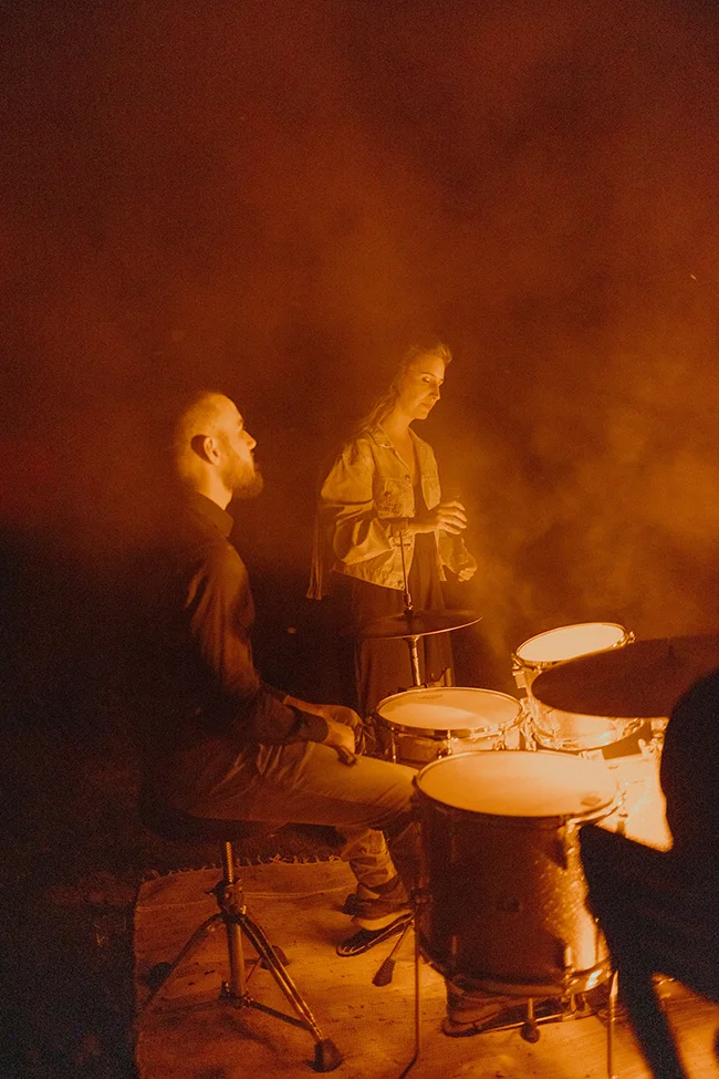 Mystérieux scène de concert sous les Pyrénées, avec un couple captivant en arrière-plan.