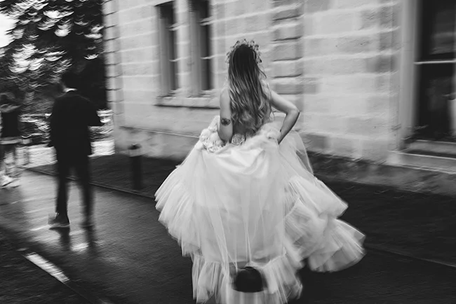 Une mariée en robe blanche légèrement floue dans une rue urbaine, capturant l'essence d'une élopement romantique.