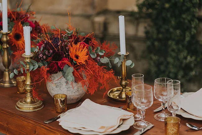 Tableau de mariage éclatant avec fleurs chaudes et luminaires, invitant la compagnie et l'élégance.