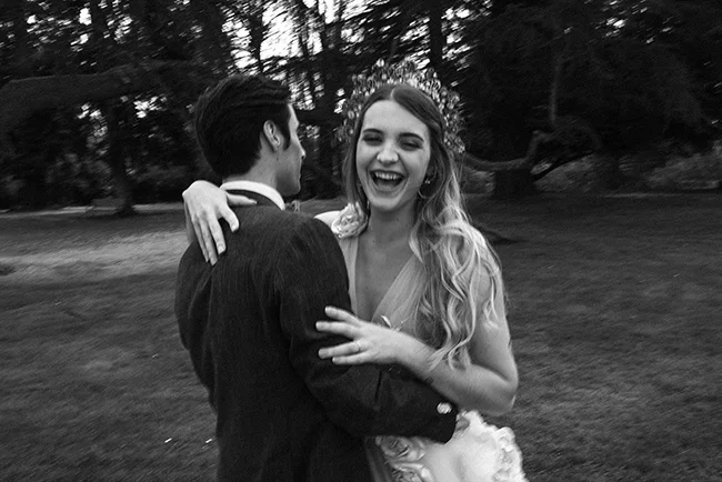 Une jeune mariée riant et heureuse s'embrassant avec son mari dans un parc romantique.
