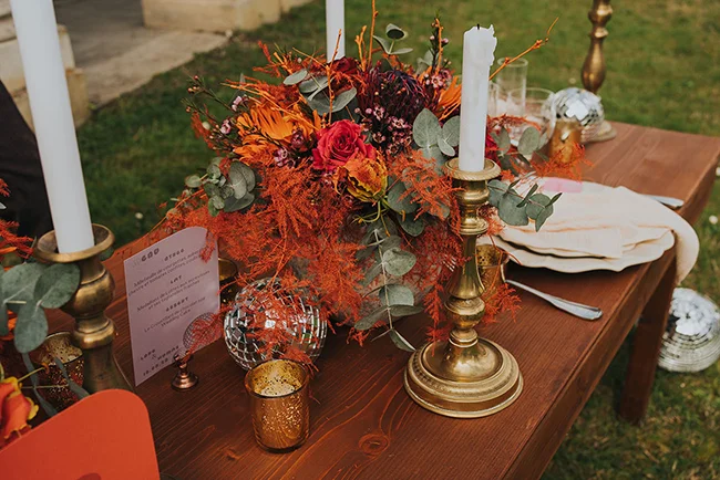 Tableau de mariage pop love avec une décoration raffinée et colorée, des cierges chauds et un bouquet vif de fleurs.
