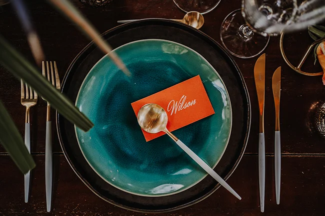 Tableau de banquet luxueux avec assiette bleu marine et place de carte rouge personnalisé, suggérant un mariage