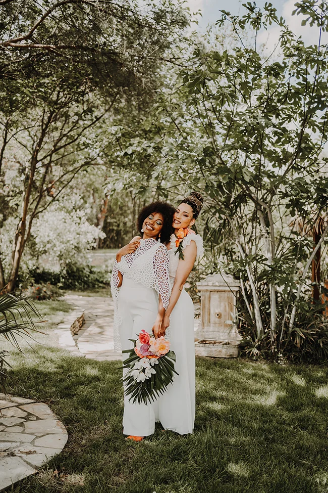 Mère et fille partageant un moment tendre dans un jardin luxuriant, incarnant l'ambiance romantique et exotique d'un mariage.