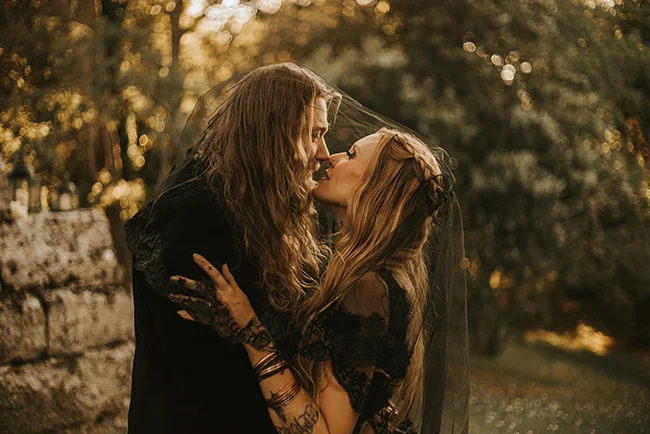 Un couple romantique partage un baiser tendre dans un décor d'ambiance sombre et élégante, parfait pour un elopement
