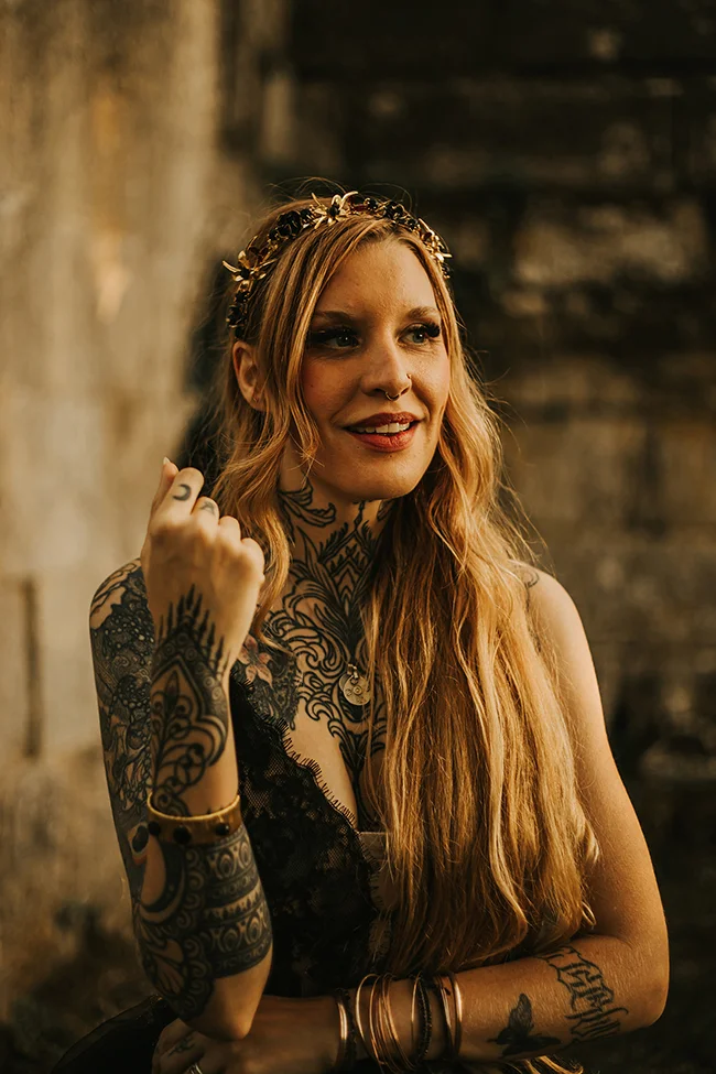 Une jeune femme éblouissante avec des tatouages luxuriants et un diadème, émettant un air mystérieux et romantique dans