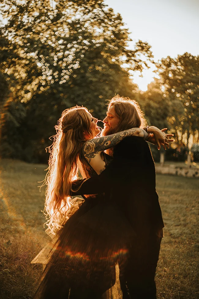Un couple éloping dark et élégant partage un moment tendre au coucher de soleil dans un parc.