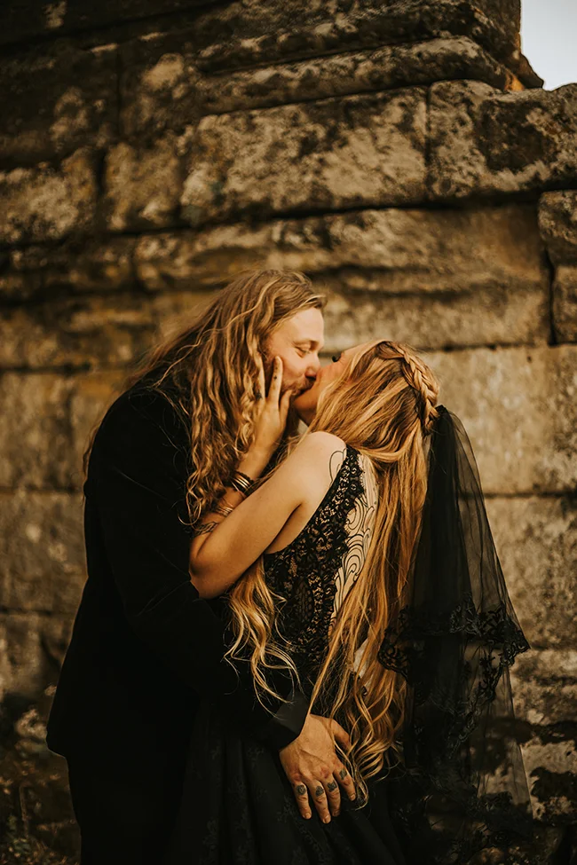 Un couple éloge l'amour sombre contre un fond de pierres anciennes.