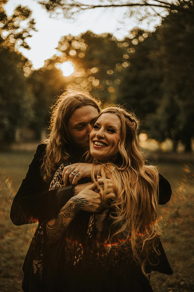 Un couple éloping dark et élégant partage un moment intime au crépuscule, leurs tatouages et bijoux ajoutant un toucher
