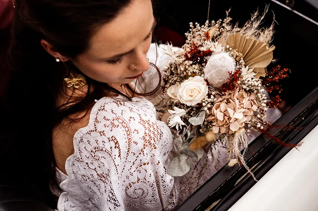 Une jeune femme dans un chemisier blanc délicat tient un bouquet romantique au Canyon du Diable, incarnant l'élégance