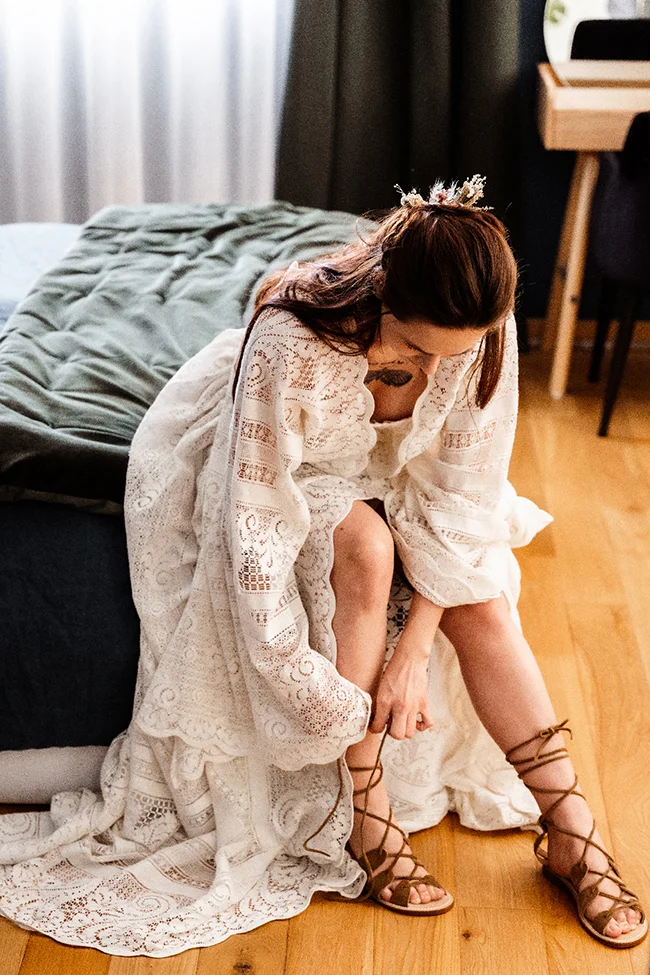 Une jeune femme dans un manteau bohémien et des sandales en cuir, se préparant pour un elopement hippie chic au Canyon