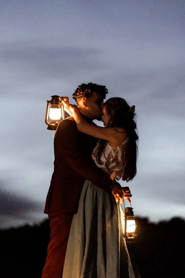 Un couple romantique se baigne dans l'ambiance chaude des lampes de paille pendant un elopement boho chic au Canyon du