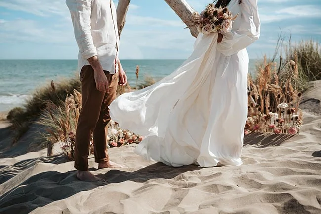 Un couple éloge leur amour sur la plage de la Camargue, vêtu d'un robe blanche élégante et d'un chemisier blanc.
