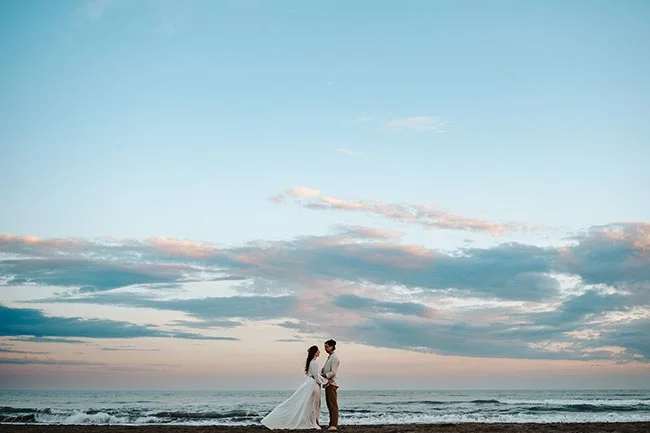 Un couple romantique se tient sur la plage de la Camargue pendant un élopement intime au crépuscule.