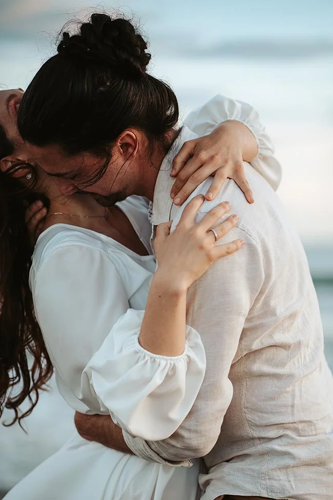 Une élopement intime sur la plage en Camargue, avec des mariés en blanc partageant un moment tendre et romantique.