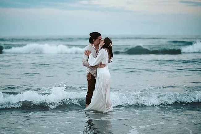 Un couple émotionnellement étreint sur la plage de la Camargue, les vagues douces suggérant un moment romantique et paisible.