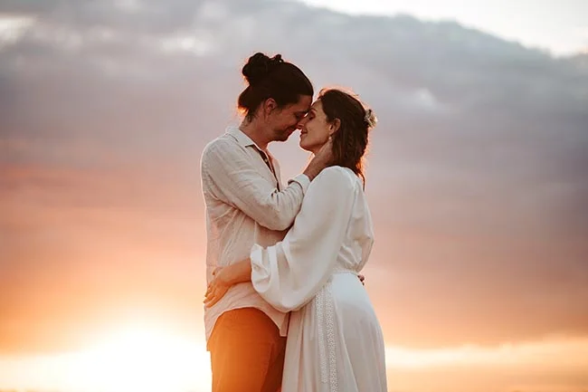 Un couple émerveillé se regarde contre un ciel d'or, un instant parfait pour un elopement intime sur la plage en Camargue.