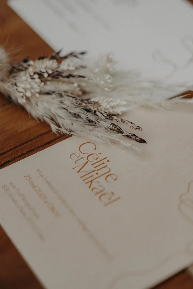 Feuilles blanches et plumes noires ornant un programme de mariage bohémien à Uzès.