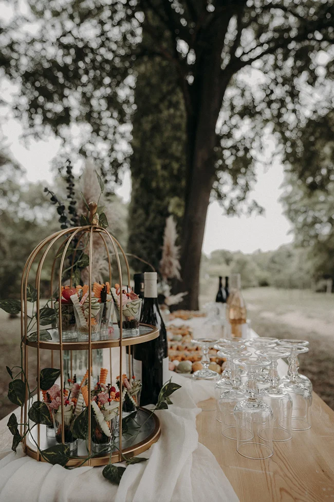 Table soignée avec charme bohémien, ornée de fruits frais et de verres d'absinthe, prête à accueillir les invités d'un