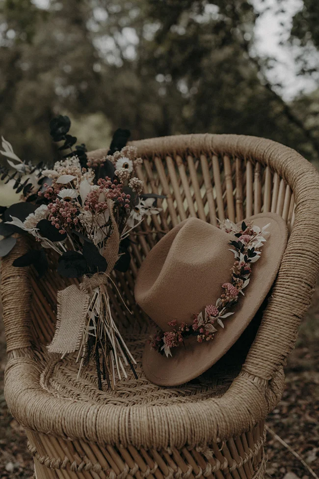 Un panier en rattan avec un chapeau et une bouquet de fleurs fraîches, idéal pour un mariage bohémien à Uzès.