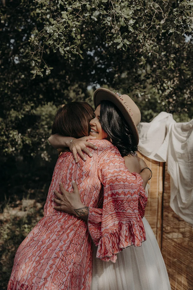Amitié tendre sous les arbres, un instant de bonheur partagé par deux femmes au cœur d'un mariage bohémien à Uzès.
