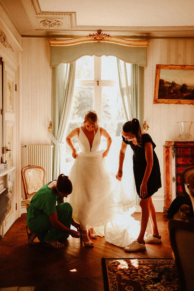 Une jeune mariée se prépare avec l'excitation et la joie, entourée de ses amies dans un salon charmant et rassurant.