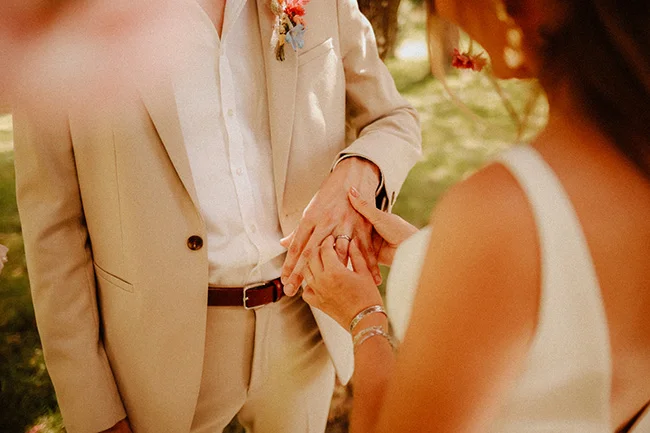 Un mariage intime, léger et coloré avec un couple qui porte des costumes blancs et un bouquet floral vif.