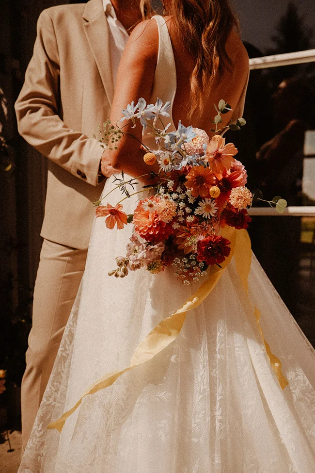 Un mariage intime, léger et coloré, avec un bouquet vibrante de fleurs fraîches et une robe blanche élégante.