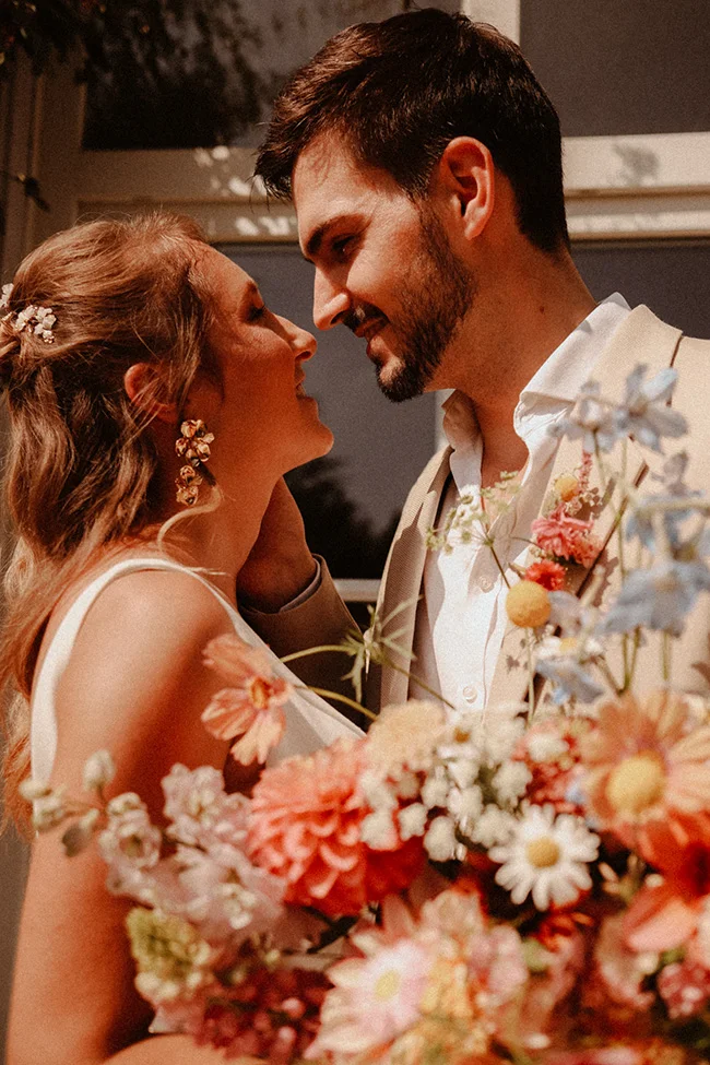 Un couple charmant partage un moment intime au milieu de fleurs colorées et douces, capturant l'essence d'un mariage