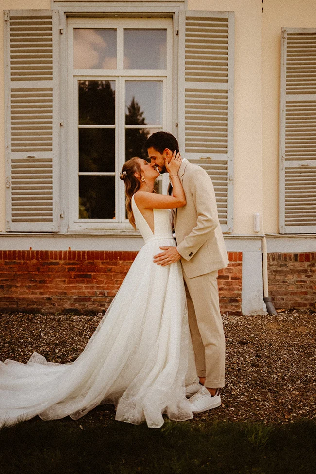 Un couple romantique et intime partage un baiser tendre devant un charmant bâtiment vintage, incarnant l'ambiance