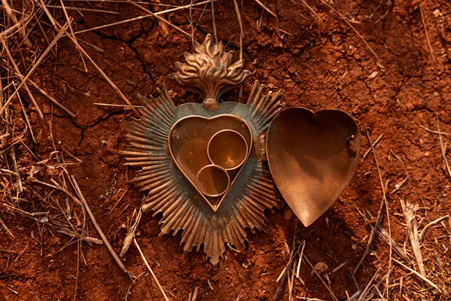 Une boîte de souvenirs métallique ouverte sur terre rouge, symbolisant un mariage spirituel et mexicain.