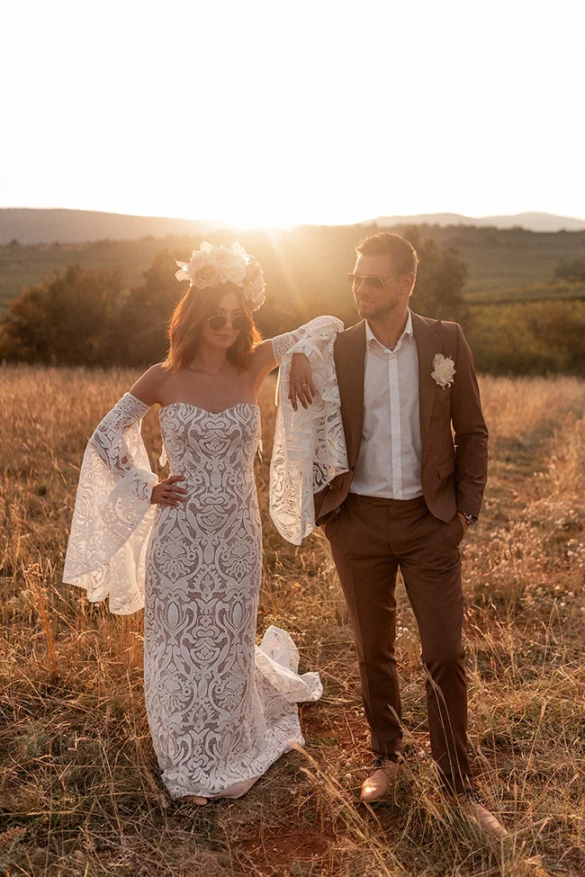 Un couple éblouissant dans des vêtements de mariage romantiques contre un fond d'horizon cérémonial ensoleillé.