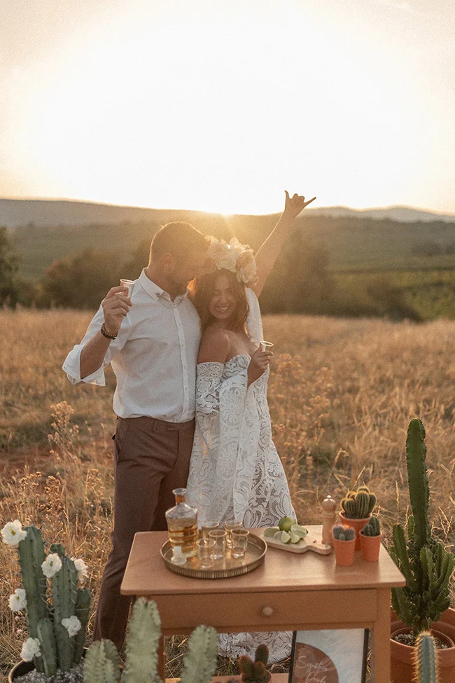 Un couple heureux dans une belle cérémonie de mariage au coucher de soleil, entouré de cactus et de décorations spirituelles.