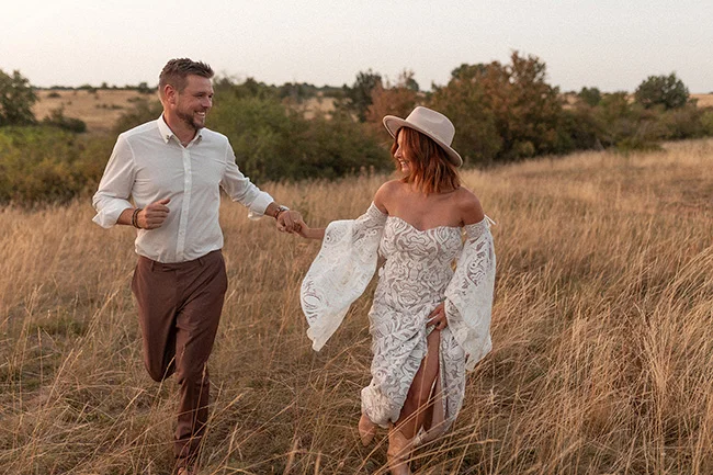 Un couple heureux dans une scène romantique au coucher de soleil dans un champ de blé sec, incarnant l'ambiance