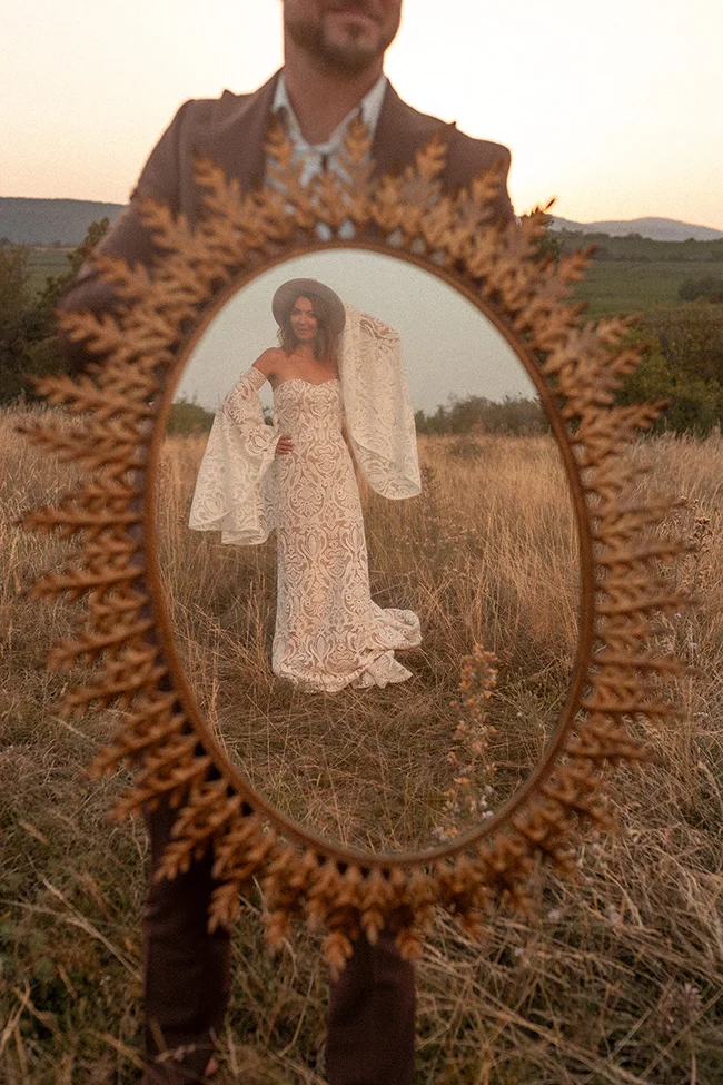 Une mariée dans un magnifique robe blanche ornée de motifs complexes se tient fièrement dans un champ, capturé dans un