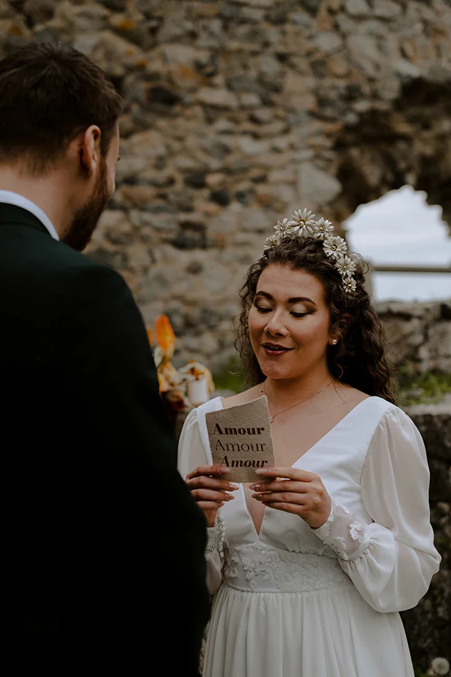 Une jeune mariée en robe blanche intime et fleurie dans un décor romantique d'anciennes ruines.