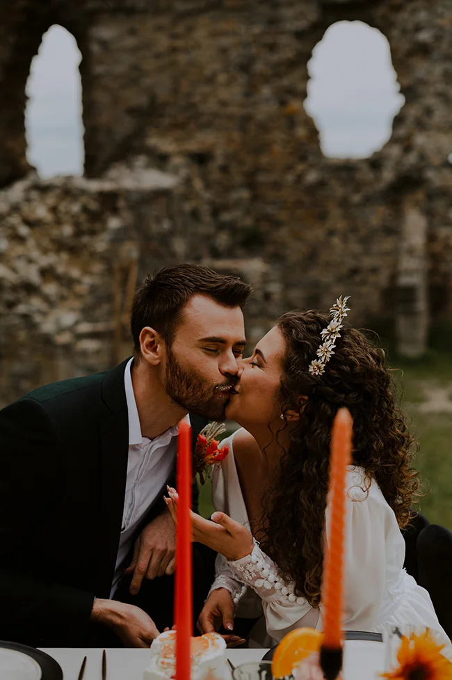Un couple romantique partage un baiser tendre au milieu des ruines historiques, célébrant leur amour avec un cake à deux.