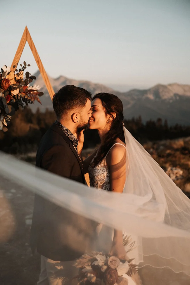 Un couple romantique partage un baiser tendre contre un décor époustouflant de montagnes, incarnant l'ambiance d'un