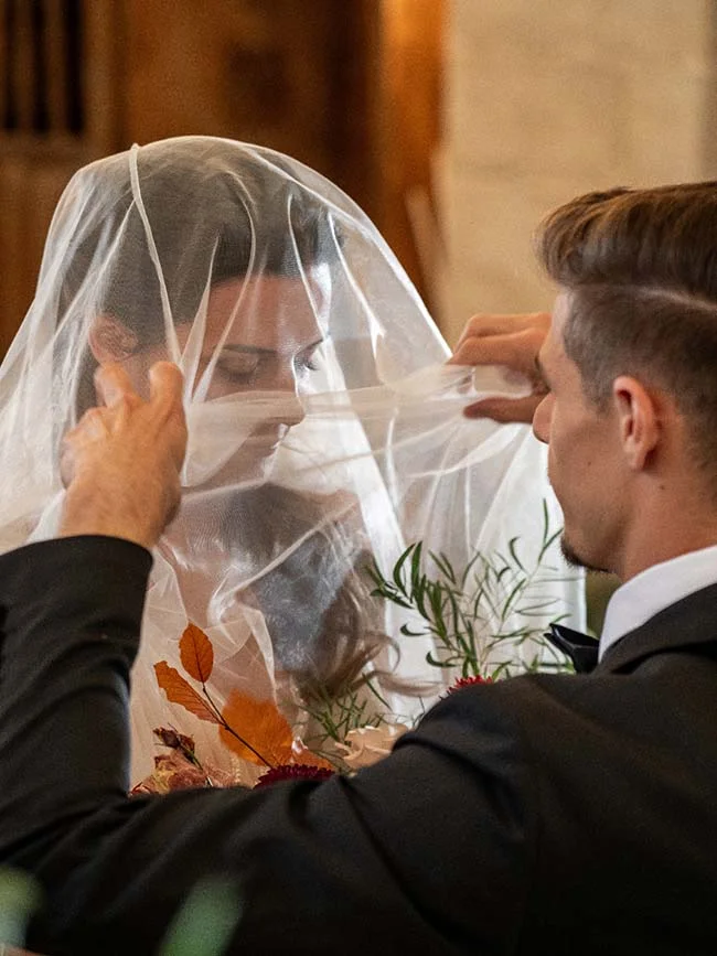 Un couple de mari et de mariée partageant un moment tendre au sein d'une église, orné de feuilles d'automne,