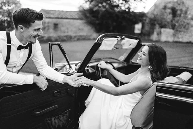 Un couple heureux dans un convertible noir, célébrant leur mariage simple et élégant.