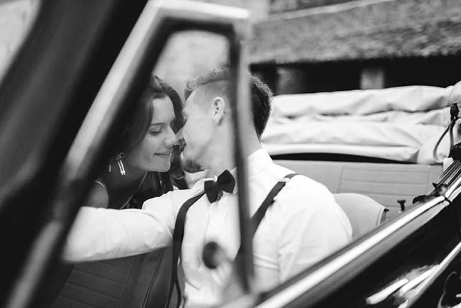 Un couple charmant dans une voiture vintage, partageant un moment tendre, incarnant l'élégance et la simplicité d'un mariage.