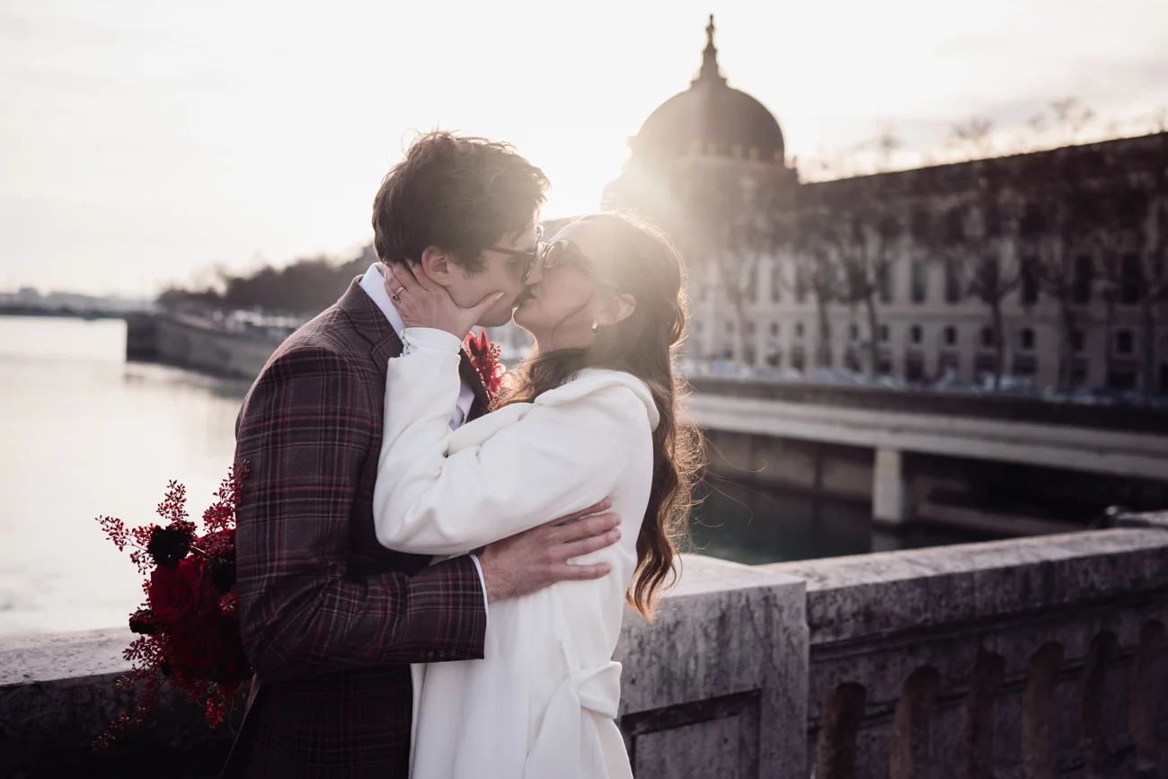 Couple élégant s'embrassant devant un monument classique au coucher du soleil, ambiance rétro chic et romantique.
