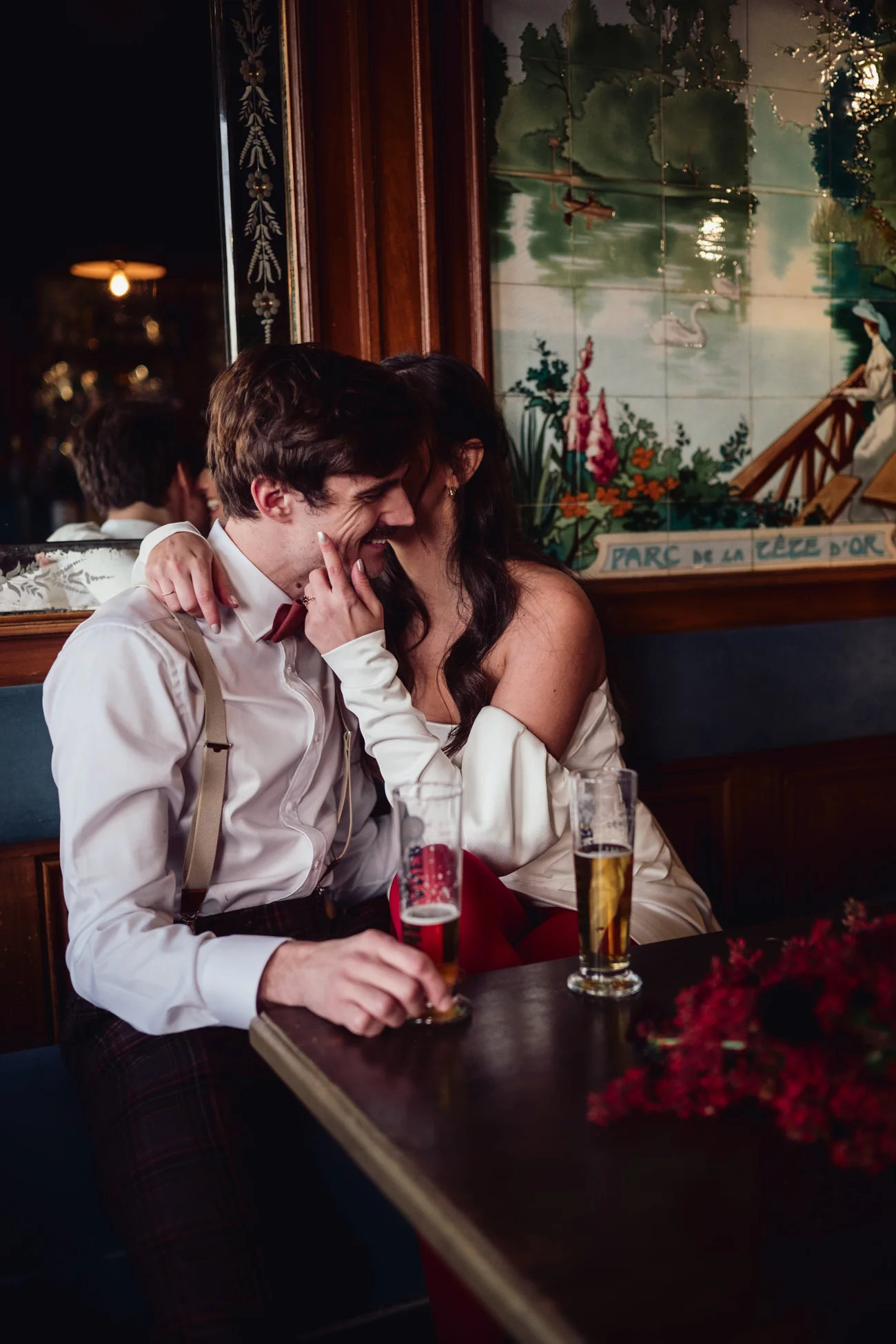 Couple complice en tenue rétro chic partageant un moment intime avec des verres de bière dans un décor vintage.